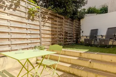 a table and chairs in a backyard with a wooden wall at Nice Magnan studio avec jardin proche des plages in Nice