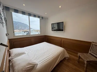 a bedroom with a bed and a tv on the wall at Seaside Serenity, Portside Apartment in Èze