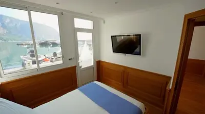 a bedroom with a large window and a tv at Seaside Serenity, Portside Apartment in Èze