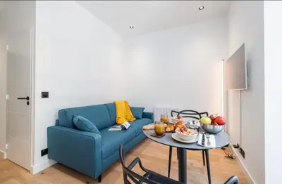 a living room with a blue couch and a table at Cozy studio near the sea in Nice