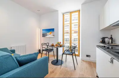 a living room with a blue couch and a table at Cozy studio near the sea in Nice