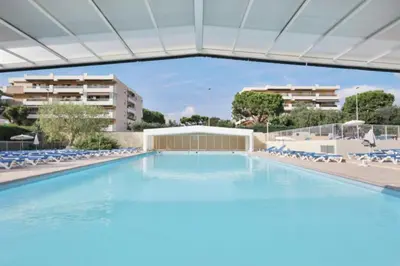 a large swimming pool with chairs and a building at Lovely 4-person studio - pool and sea in Cros-de-Cagnes