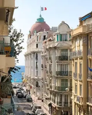 a building with a flag on top of it on a street at Superbe appartement, aperçu mer, Negresco-centre in Nice