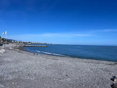 a rocky beach with a flag on the shore at duplex en bord de mer in Cagnes-sur-Mer