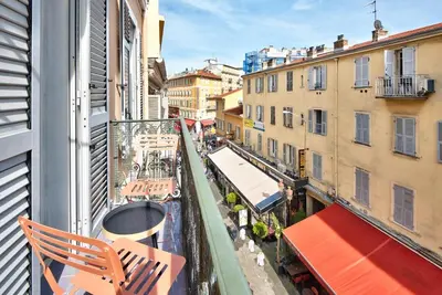 a balcony with chairs and tables on a city street at Appartement Cosy centre Nice in Nice
