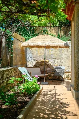 a patio with a straw umbrella and two chairs at Villa Mi Rancho Vue mer - Jardin - Plage et resto à 5 min in Villefranche-sur-Mer