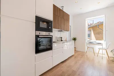 a kitchen with white cabinets and a table and a window at Appartement neuf 2 pièces Port in Nice