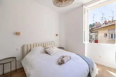 a white bedroom with a bed with towels on it at Appartement neuf 2 pièces Port in Nice