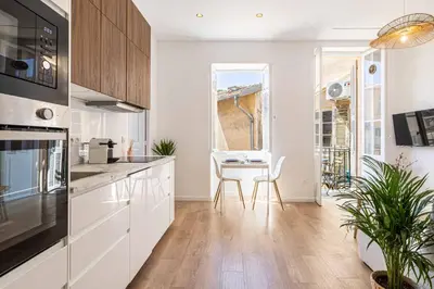 a kitchen with white cabinets and a table and a window at Appartement neuf 2 pièces Port in Nice
