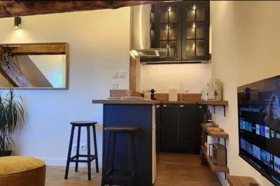 a kitchen with black cabinets and a bar with stools at MY CASA - GRIMALDI - Sous les toits de Nice in Nice