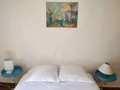 a bed with two pillows and a painting on the wall at Appartement à deux pas de la plage in Nice