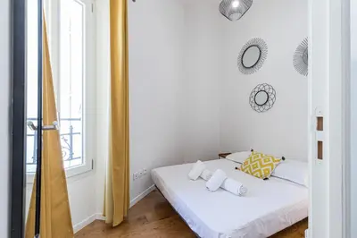 a bedroom with a bed with white sheets and a mirror at 33 GAMBETTA - Appartement 2 pieces Mezzanine in Nice