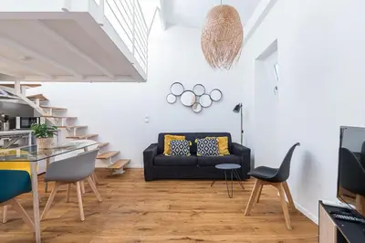 a living room with a black couch and stairs at 33 GAMBETTA - Appartement 2 pieces Mezzanine in Nice