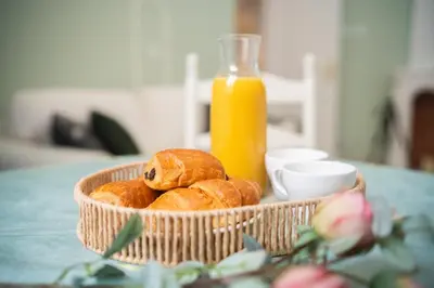 a bowl of pastries on a table with a bottle of orange juice at Cozy Apartment in Old Town Nice in Nice