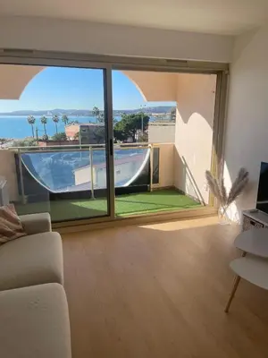 a living room with a large window with a view of a pool at Sea View Apartment 50 m to Beach FREE Parking in Cagnes-sur-Mer