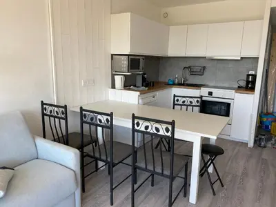 a kitchen with a table and chairs and a couch at Appartement Résidence Héliotel in Saint-Laurent-du-Var