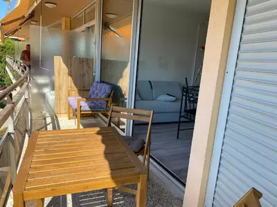 a patio with a wooden table and chairs on a balcony at Appartement Résidence Héliotel in Saint-Laurent-du-Var