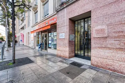 a red brick building with a woman walking down a street at Cocon D'Azur - 5min from the beach - Happy Rentals in Nice