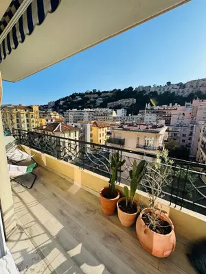 a balcony with potted plants and a view of a city at Nice experience in Nice