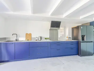 a large kitchen with blue cabinets and a refrigerator at Holiday Home Villa la Bergerie by Interhome in Nice