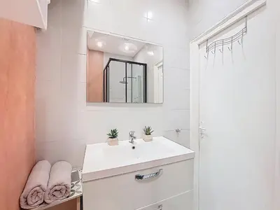 a white bathroom with a sink and a mirror at Apartment Le Gambetta by Interhome in Nice