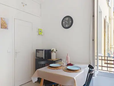 a dining room table with a clock on the wall at Apartment Le Gambetta by Interhome in Nice
