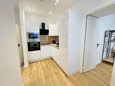 a kitchen with white cabinets and a wooden floor at RF104 - Charmant 3P à nice près du Port in Nice