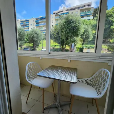 a table and two chairs in front of a window at Charmant appartement au calme à proximité du Port, de la vieille ville de Nice , de la Promenade des Anglais in Nice