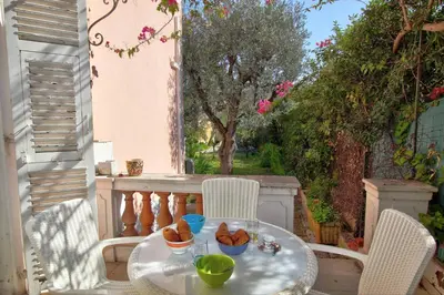 a table and chairs on a balcony with food on it at Villa La Rara Beaulieu Centre in Beaulieu-sur-Mer