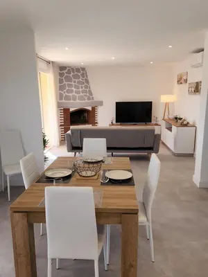 a living room with a wooden table and white chairs at Superbe appartement vue mer in Cagnes-sur-Mer