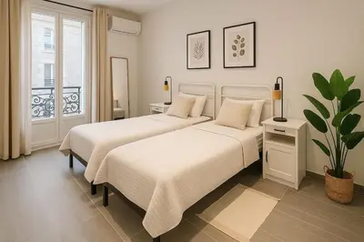 two beds in a white room with a window at Charmant appartement 3 grandes chambres au coeur de Nice au calme absolu in Nice