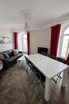 a living room with a white table and red curtains at Splendide appartement design plein centre nice climatisé - 3 chambres in Nice