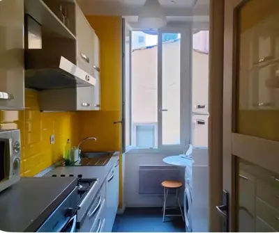 a kitchen with yellow walls and a sink and a window at Appart Le Carré D'Or in Nice