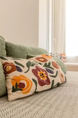 a pillow on a couch with flowers on it at Nice Magnan, Appartement proches plage et tramway in Nice