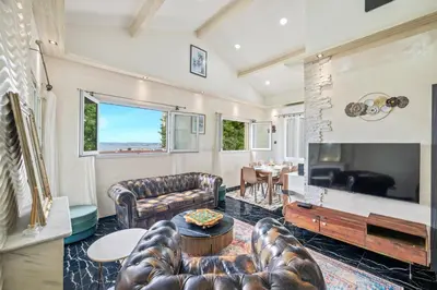a living room with leather furniture and a large television at Villa Nissarda, Maison Niçoise avec vue mer, parking, à 5 minutes du port in Nice