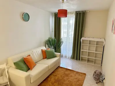 a living room with a white couch with colorful pillows at Studio Riviera - balcon et Wifi in Nice