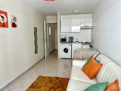 a living room with a white couch and a kitchen at Studio Riviera - balcon et Wifi in Nice