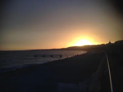 a sunset on the beach with the sun setting at Long stay in Old town of Nice, Castle Hill in Nice