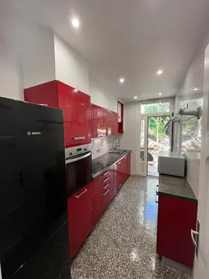a kitchen with red cabinets and a black refrigerator at Seaside Jungle Retreat in Nice