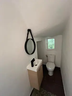 a bathroom with a toilet and a mirror on the wall at Seaside Jungle Retreat in Nice