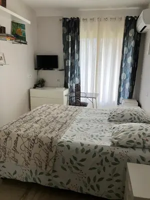 a bedroom with a bed and a table and a window at Chambre de charme in Nice