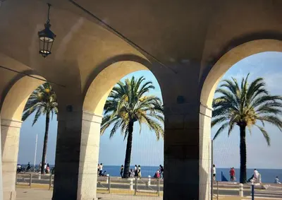 an archway with palm trees and the ocean in the background at A Studio at Nice Beach in Nice