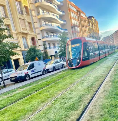 a red tram traveling down a city street with cars at A Studio at Nice Beach in Nice