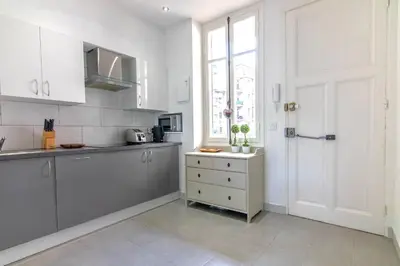 a kitchen with white cabinets and a window and a door at Résidence Estienne d'Orves in Nice