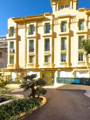 a large yellow building with palm trees in front of it at Depoilly 3 Pers Centrale WiFi in Nice