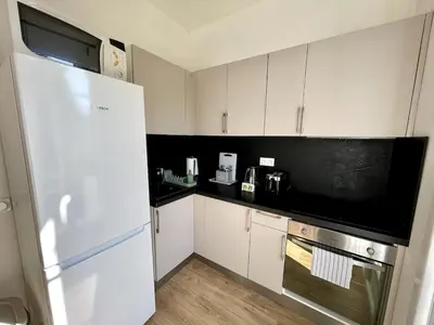 a kitchen with white cabinets and a white refrigerator at Studio proche mer, avec terrasse et parking in Nice