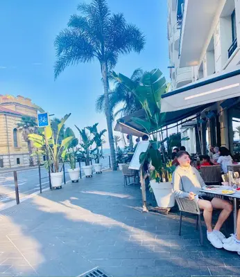 a woman sitting at a table next to the beach at A room in Nice Beach in Nice