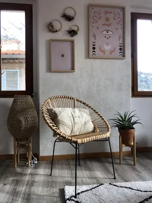 a wicker chair sitting in a room with a wall at Cosy Studio Sea view in Villefranche-sur-Mer