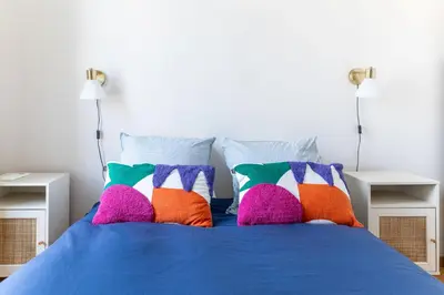 a blue bed with colorful pillows on it at Happyfew Cathedrale in Nice