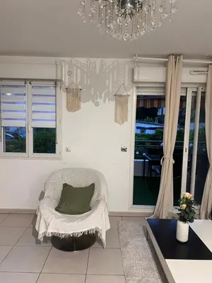 a living room with a chair and a chandelier at Appartement rénové , Climatisé, Terrasse, Parking en sous sol in Saint-Laurent-du-Var